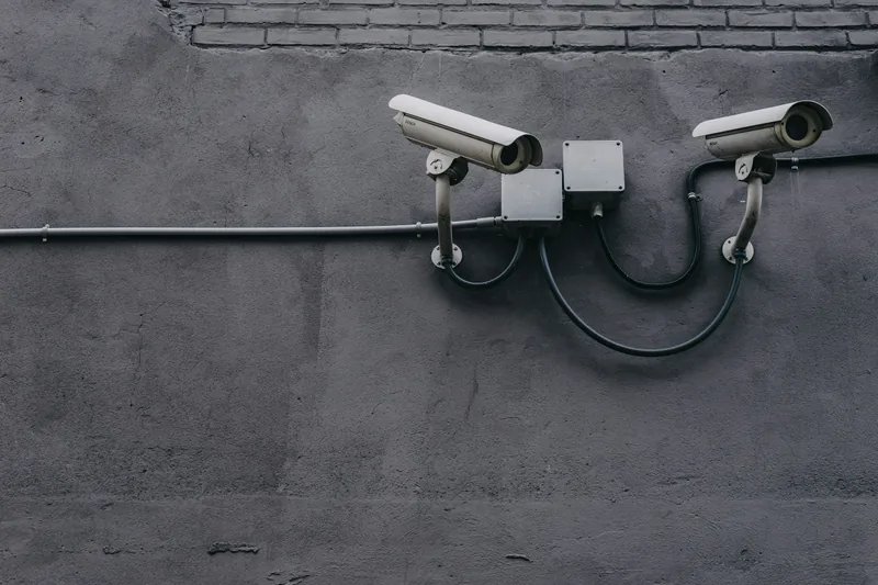 Two bullet surveillance cameras mounted on a concrete wall