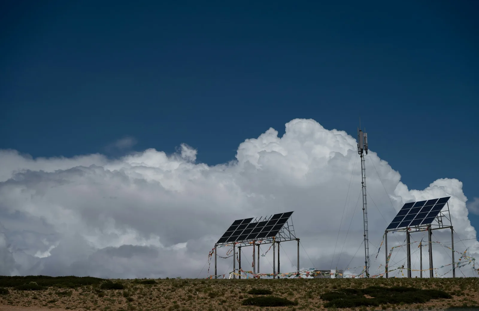 Solar panels and a telecommunications tower under a cloudy sky