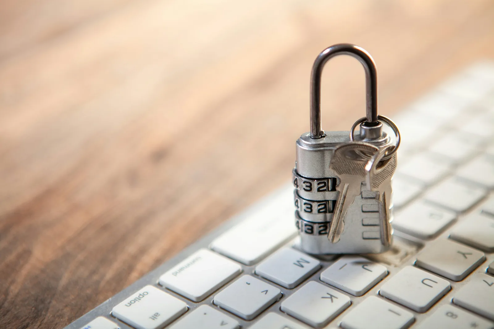 A small padlock and a set of keys resting on a keyboard