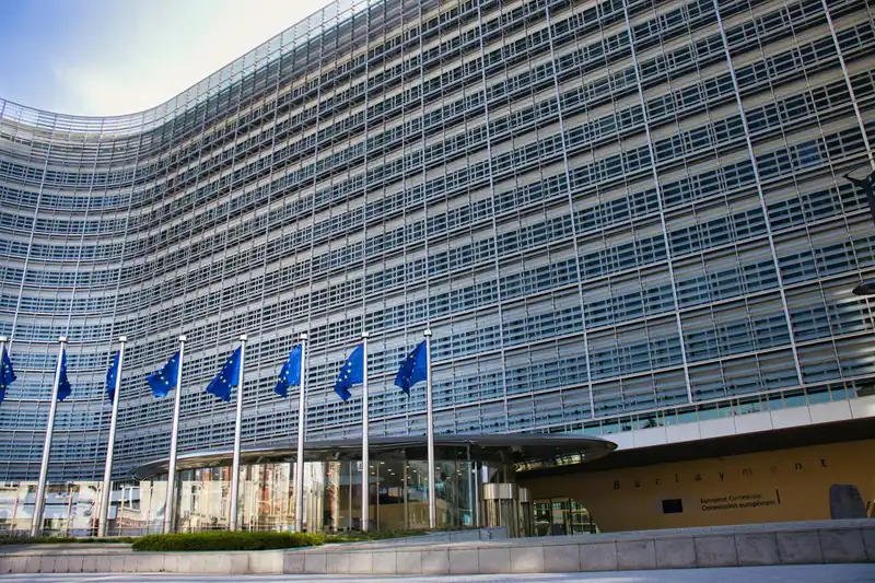 A modern glass building with a row of European Union flags